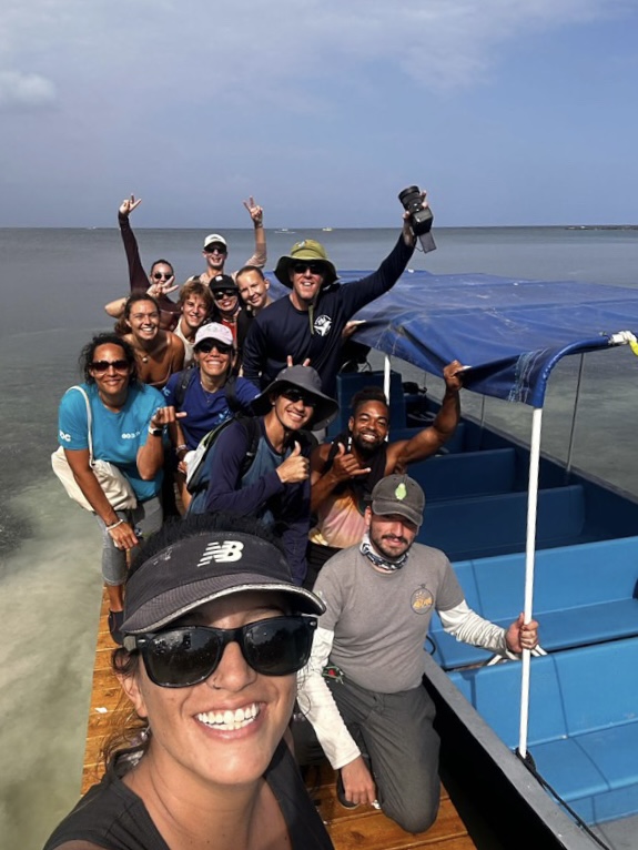 group photo on a deck, by a boat with the sea in the background
